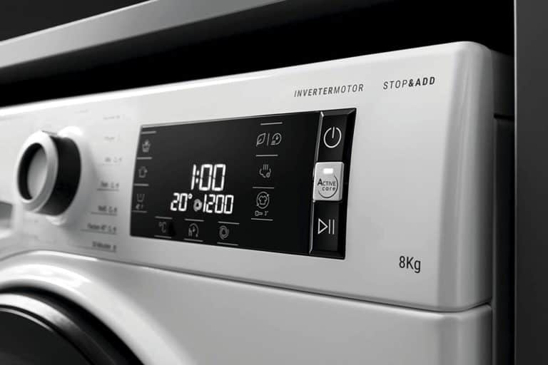 Nahaufnahme des Displays der Bauknecht-Waschmaschine W Active 823 PS: Links Drehregler mit Beschriftung (unscharf); mittig schwarzes Touchscreen-Display mit Symbolen, Zeitabgabe (1:00), Temperaturangabe (20°) und Schleuderdrehzahl (1200); rechts mehrere Beschriftungen auf der weißen Blendenleiste: "Invertermotor", "Stop&Add", "8 kg"