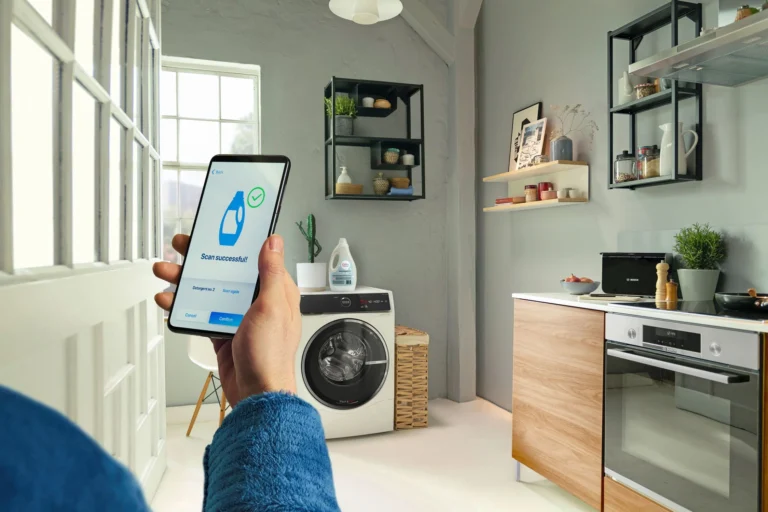 Bosch Waschmaschine in Küche, Hand hält Smartphone mit der Nachricht "Scan abgeschlossen", Quelle: Bosch